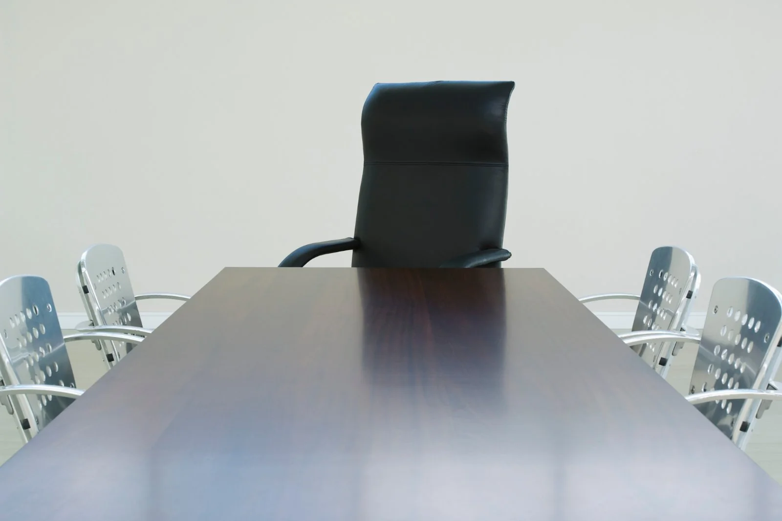 Empty leather chair at the head of a boardroom table, surrounded by occupied seats. The visual anchor for angling's missing seat at the policy table.